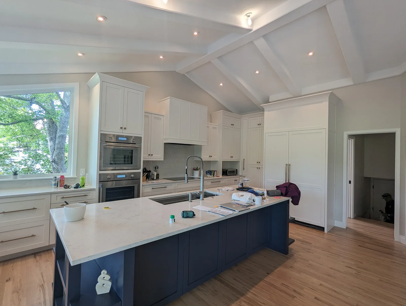 Large vaulted kitchen with white perimeter cabinets and a navy island