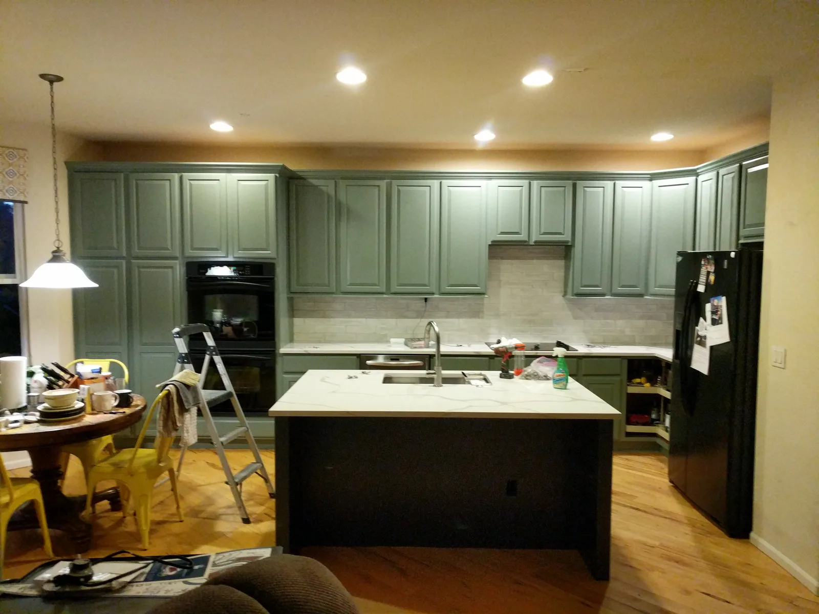 A kitchen halfway through refinishing, with a ladder in the middle of the room and doors away at the shop