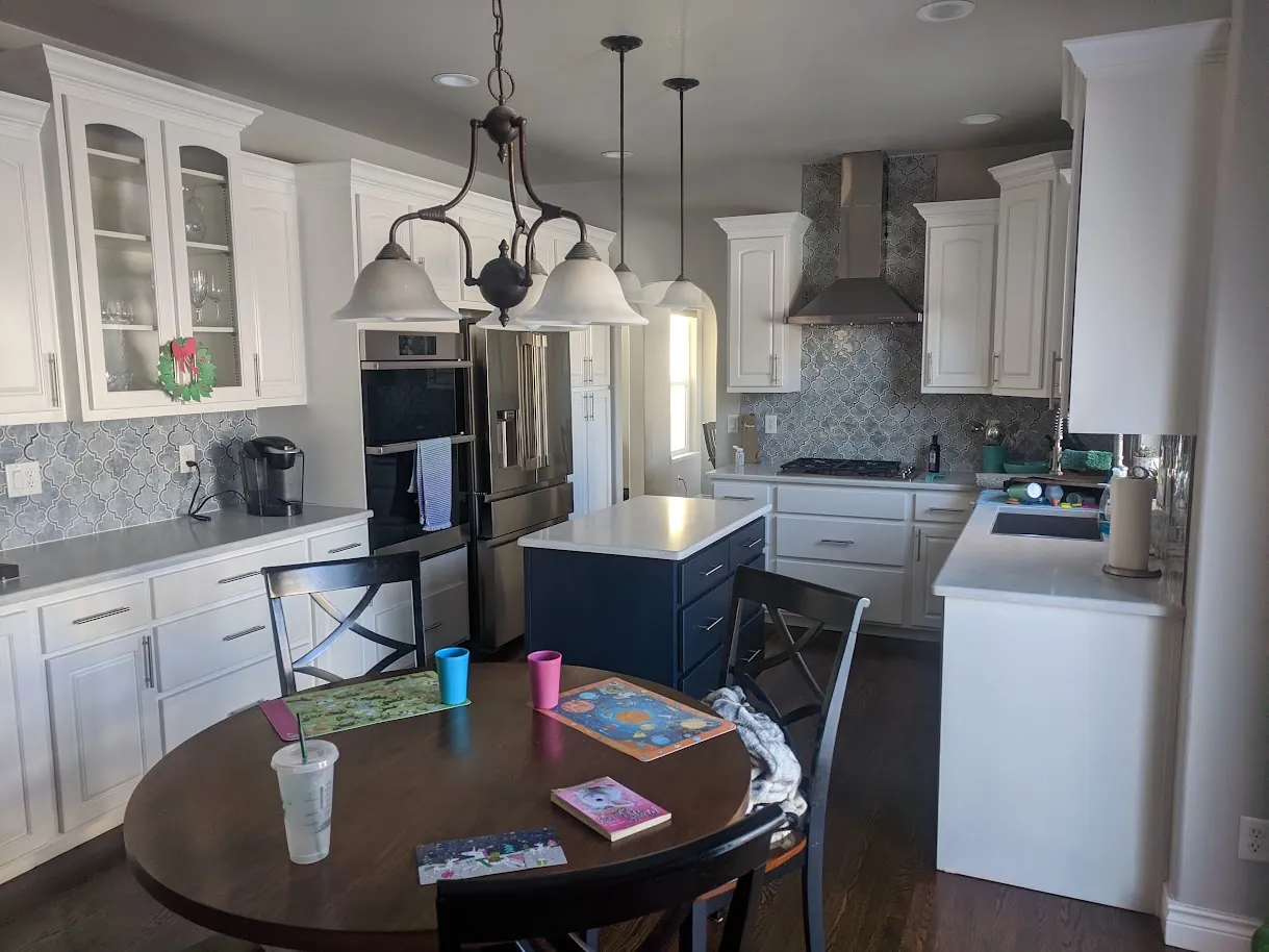 After: refinished two-tone kitchen with Pure White cabinets and a Naval island