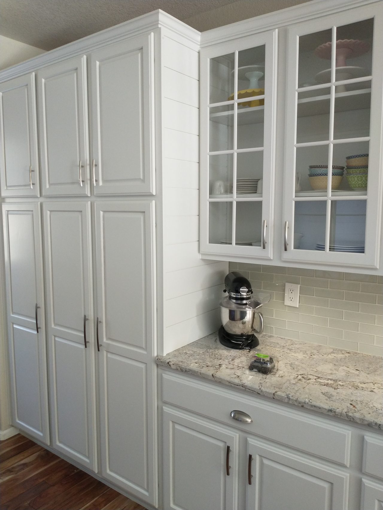 White cabinetry with glass display doors and a grey island