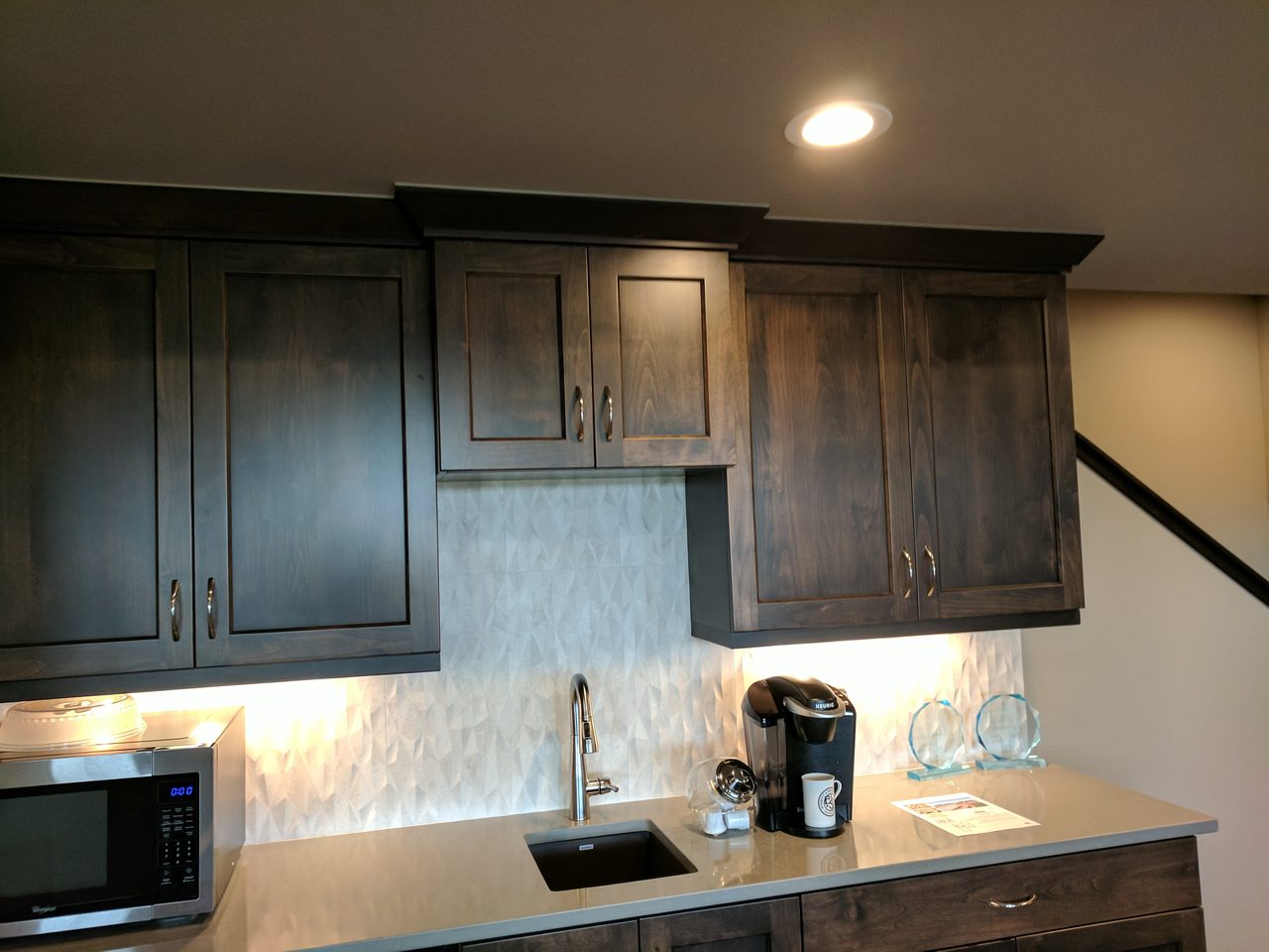Kitchen with richly finished dark cabinetry and light counters