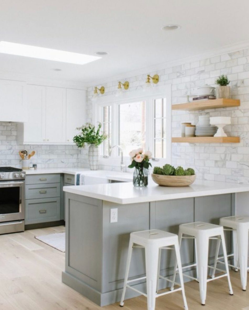 White kitchen with a grey island and floating wood shelves